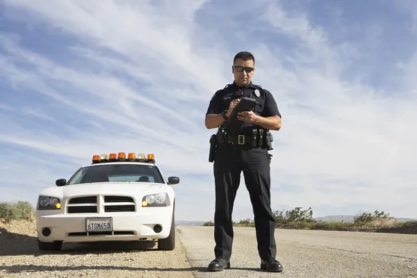 Офицер полиции делать заметки перед автомобилем — стоковое фото